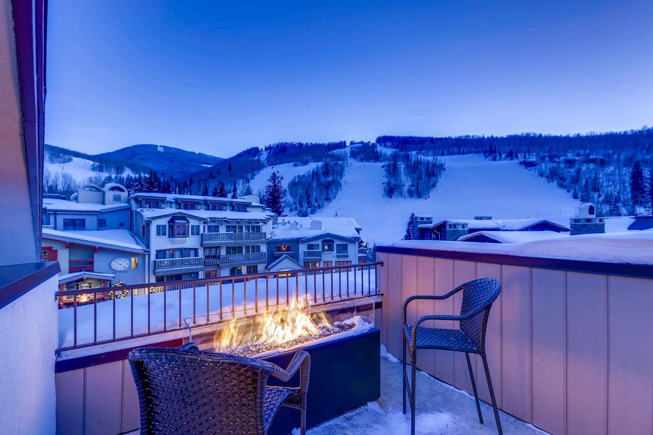 Private deck with fire pit overlooking snowy ski slopes at dusk