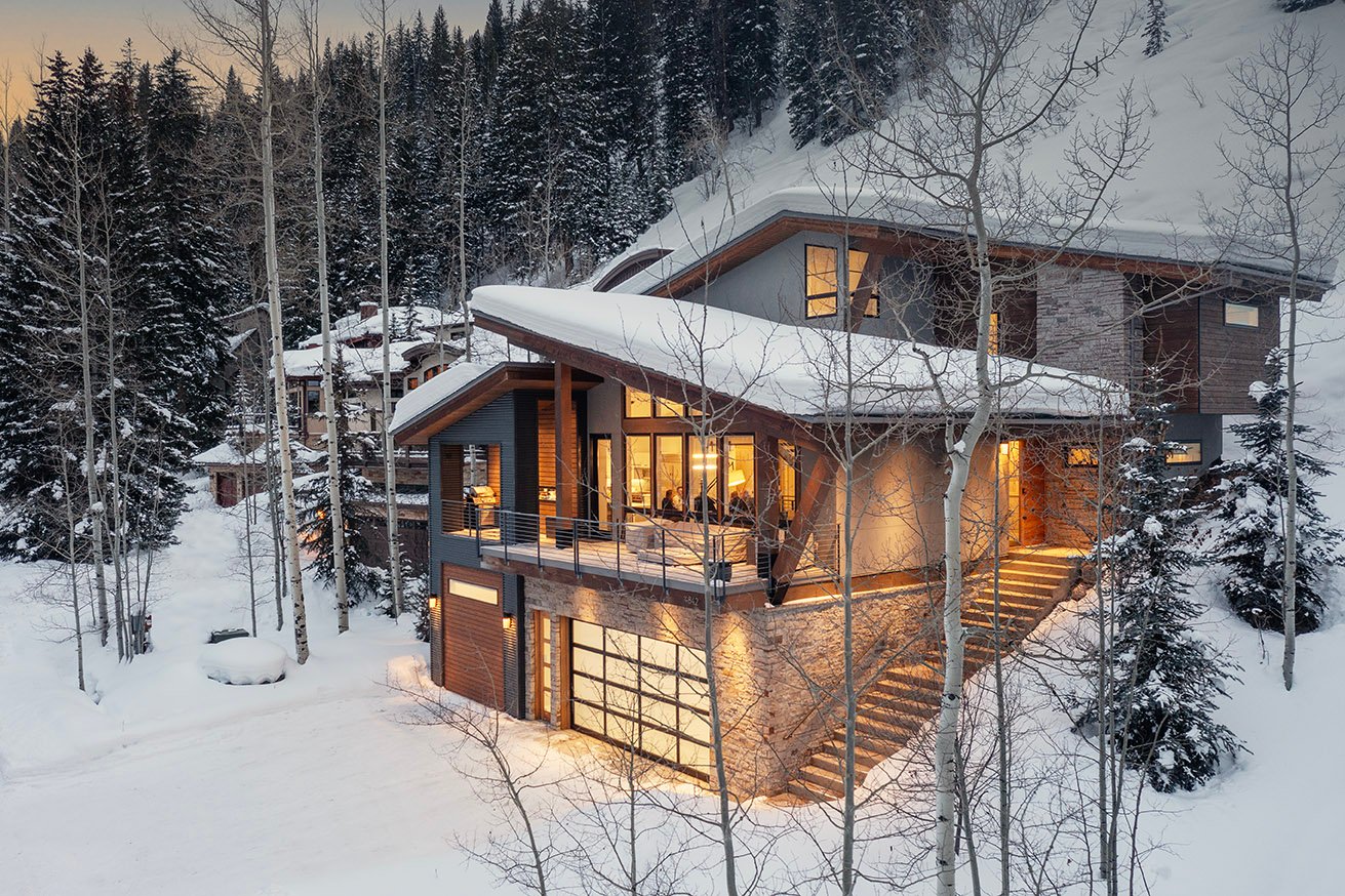 Après Chalet, a modern East Vail vacation home, glowing on a snowy evening