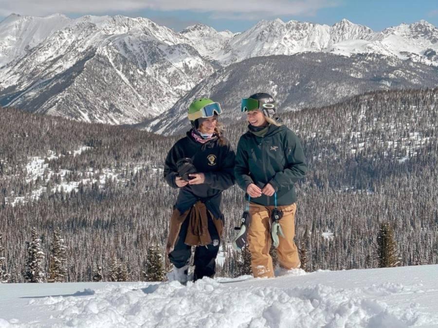 Two skiers on the mountain above the Vail Valley with the Gore Range behind them